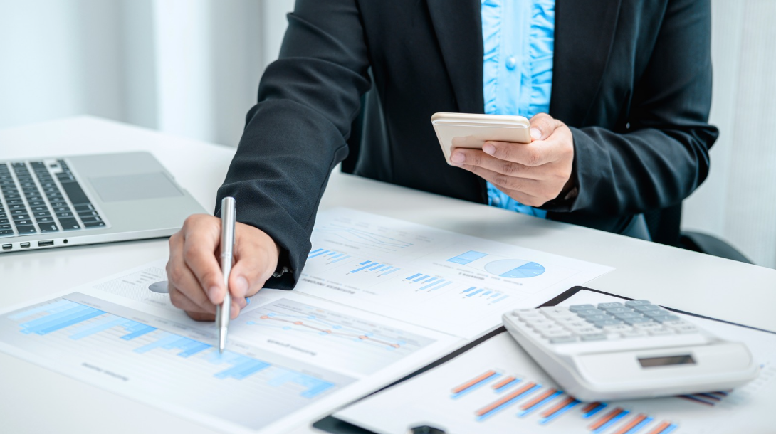 Investor reviewing home loan performance charts and trust deed offerings on mobile phone and paper, with Pacific Direct Mortgage
